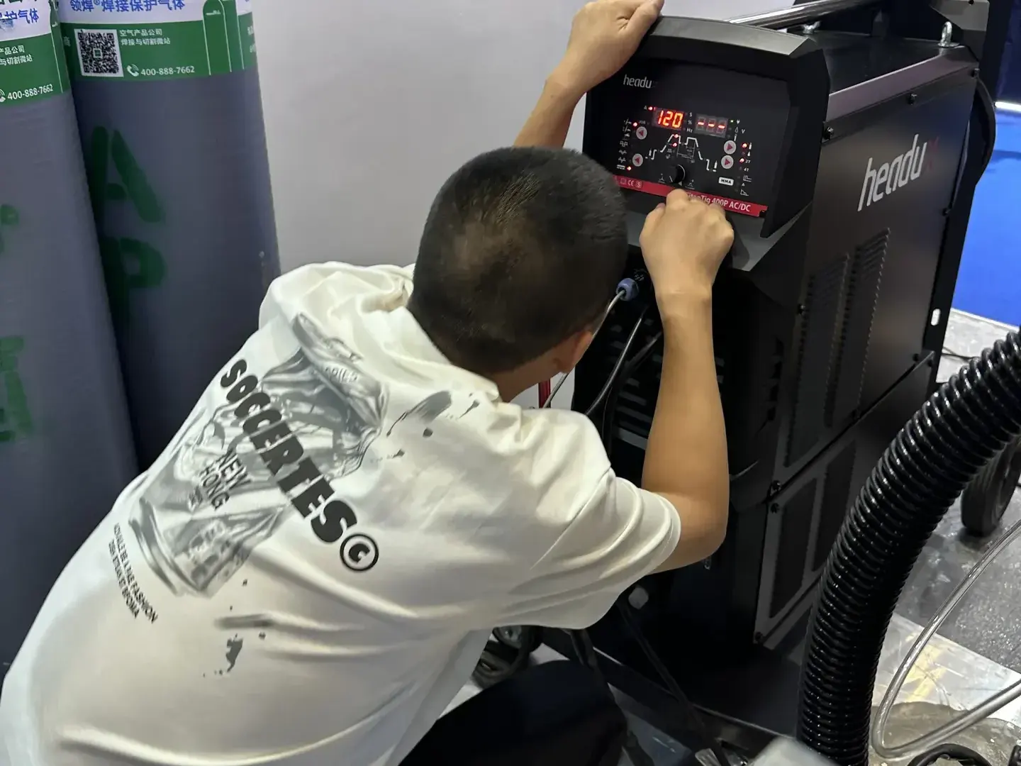 Customer adjusting an industrial welding power source at the HEADUX booth